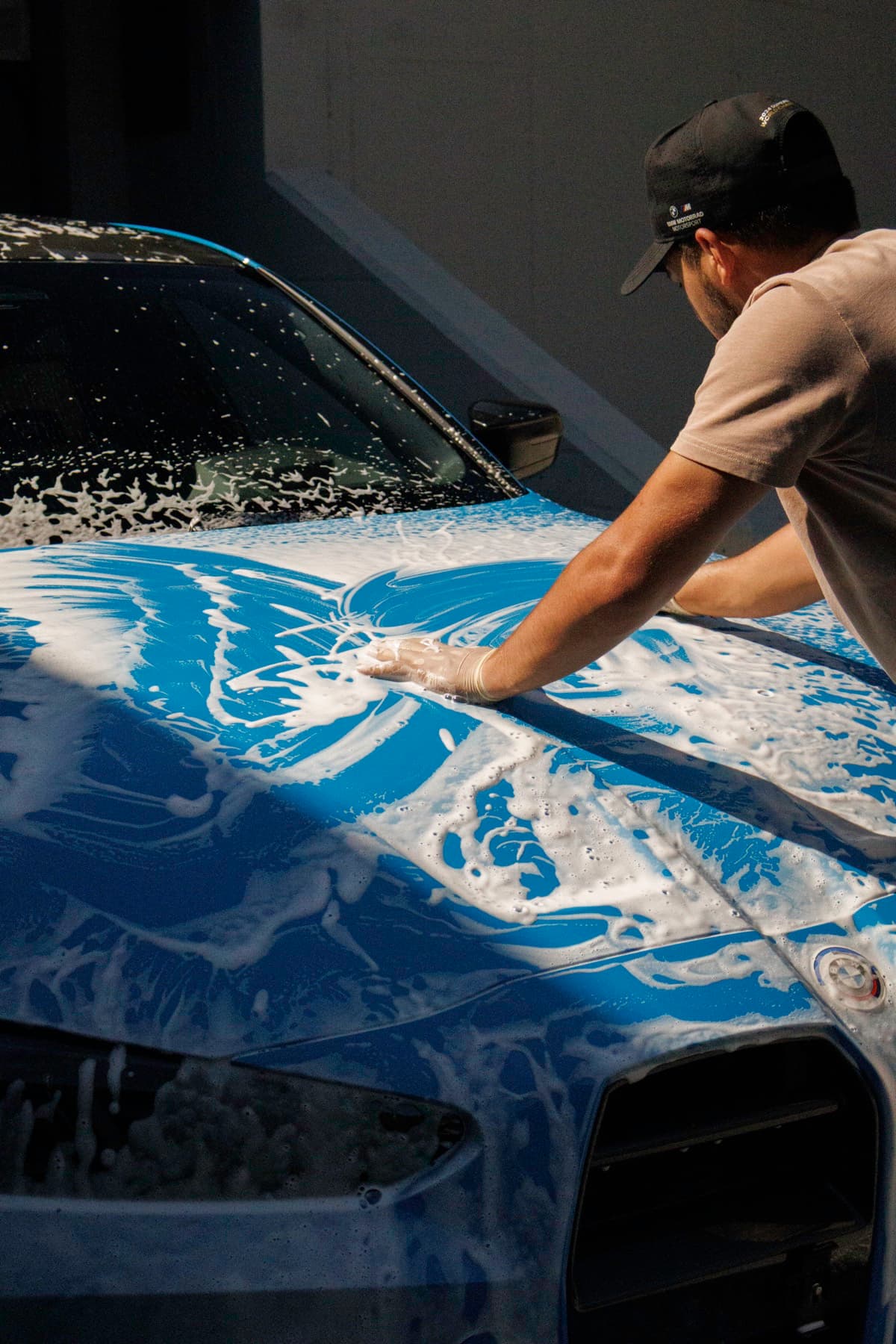 Motorhaube eines BMW wird mit Snow Foam von Hand gewaschen